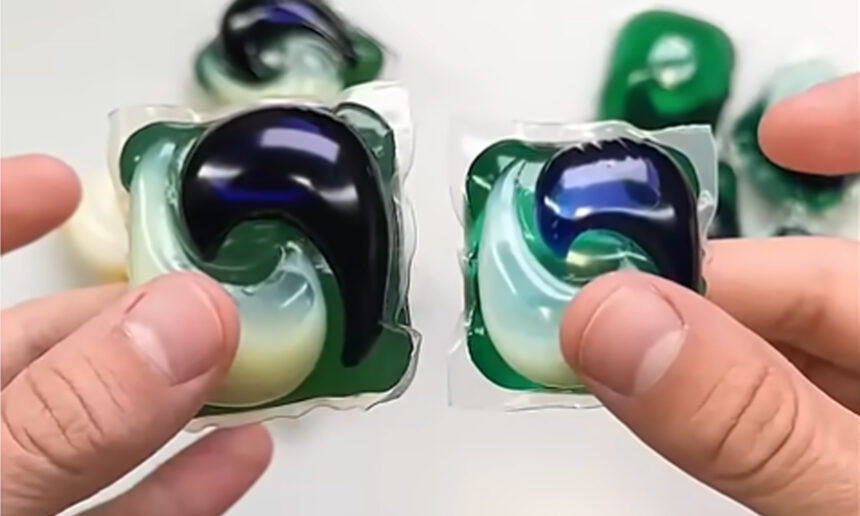 κοντινή εικόνα χεριού που κρατάει 2 Pods πλυντήριου ρούχων