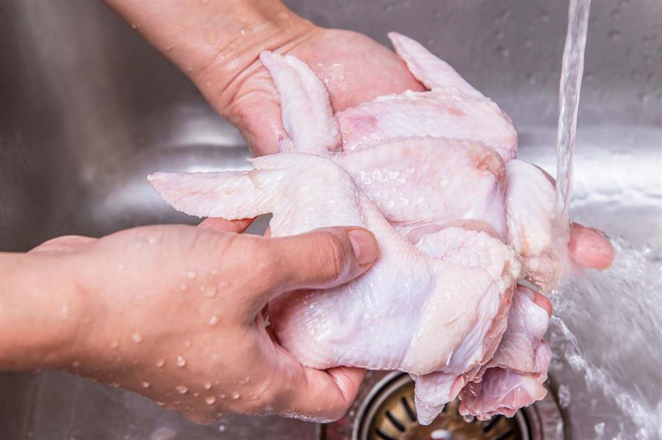 Εικόνα που δείχνει 2 χέρια να πλένει ωμό κοτόπουλο μέσα σε νεροχύτη ανοξείδωτο