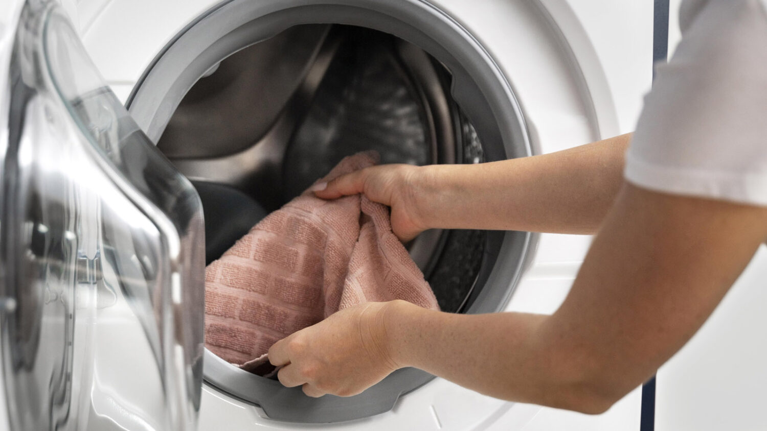 γυναίκα βάζει πετσέτα στο πλυντήριο