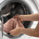 γυναίκα βάζει πετσέτα στο πλυντήριο