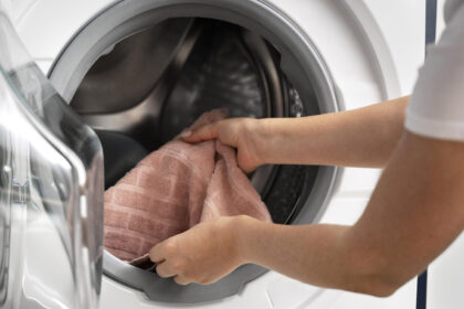 γυναίκα βάζει πετσέτα στο πλυντήριο