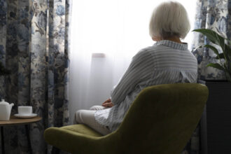 Μόνη ηλικιωμένη γυναίκα κοιτάει από το παράθυρο